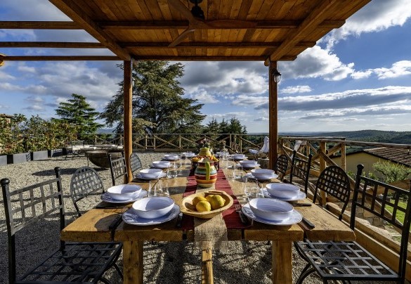 Il tavolo da pranzo all’aperto, accanto alla cucina esterna, ombreggiato dalla pergola - I Tramonti