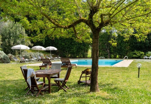 Un angolo di relax sotto lo Spino di Giuda, guardando la piscina - Villa Delle Silerchie