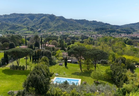 La piscina, il parco, la villa e sullo sfondo l’abitato di Camaiore - Villa Delle Silerchie